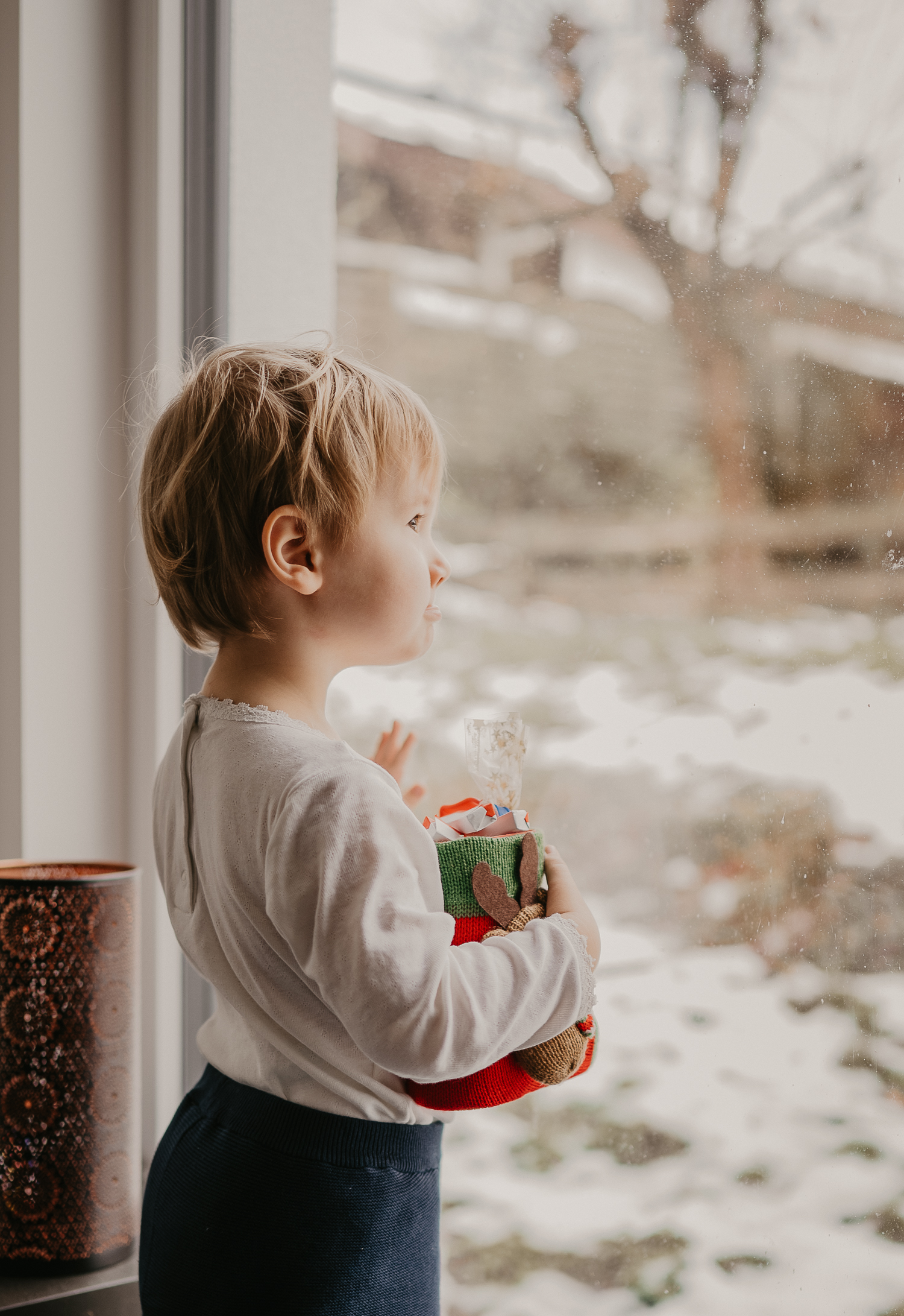 Kind hält stolz seinen Nikolausstiefel im Arm und schaut aus dem Fenster
