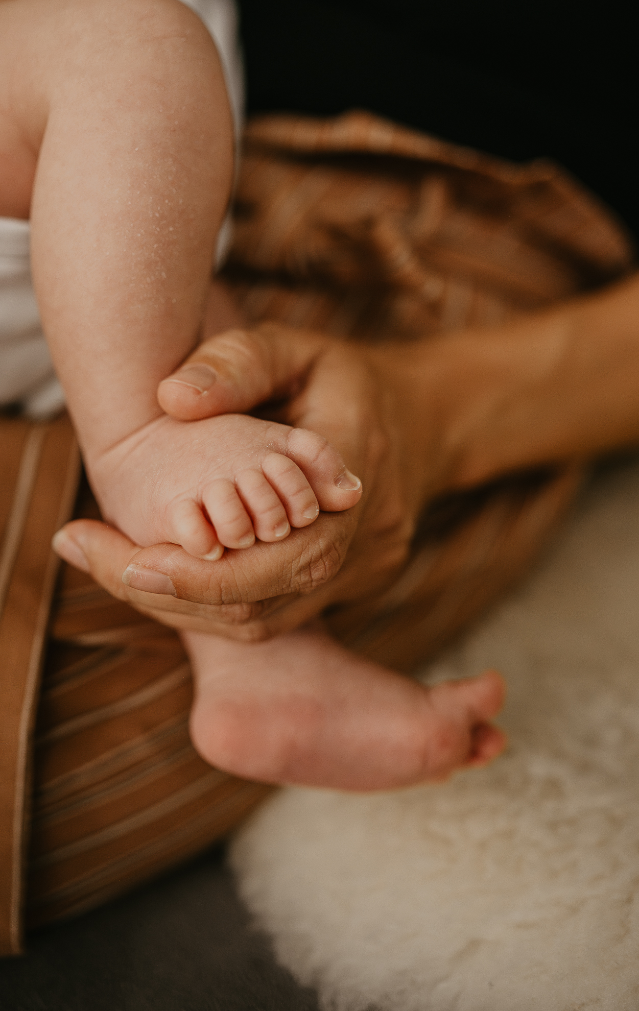 Mit Feingefühl, Erfahrung und einem Blick für die kleinen Details schaffe ich Bilder, die eure Verbindung sichtbar machen. Wie hier auf einem Detailbild der Babyfüsse. Die Mama hält ihr Neugeborenes gerade zärtlich im Arm und stillt es