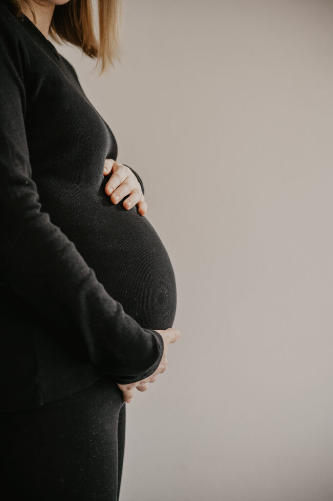 Eine schwangere Frau hält ihren Babybauch beim Babybauchshooting im Kreis Esslingen