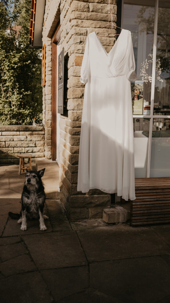Brautkleid hängt an einem Bügel und flattert bei einer Sommerhochzeit im Wind